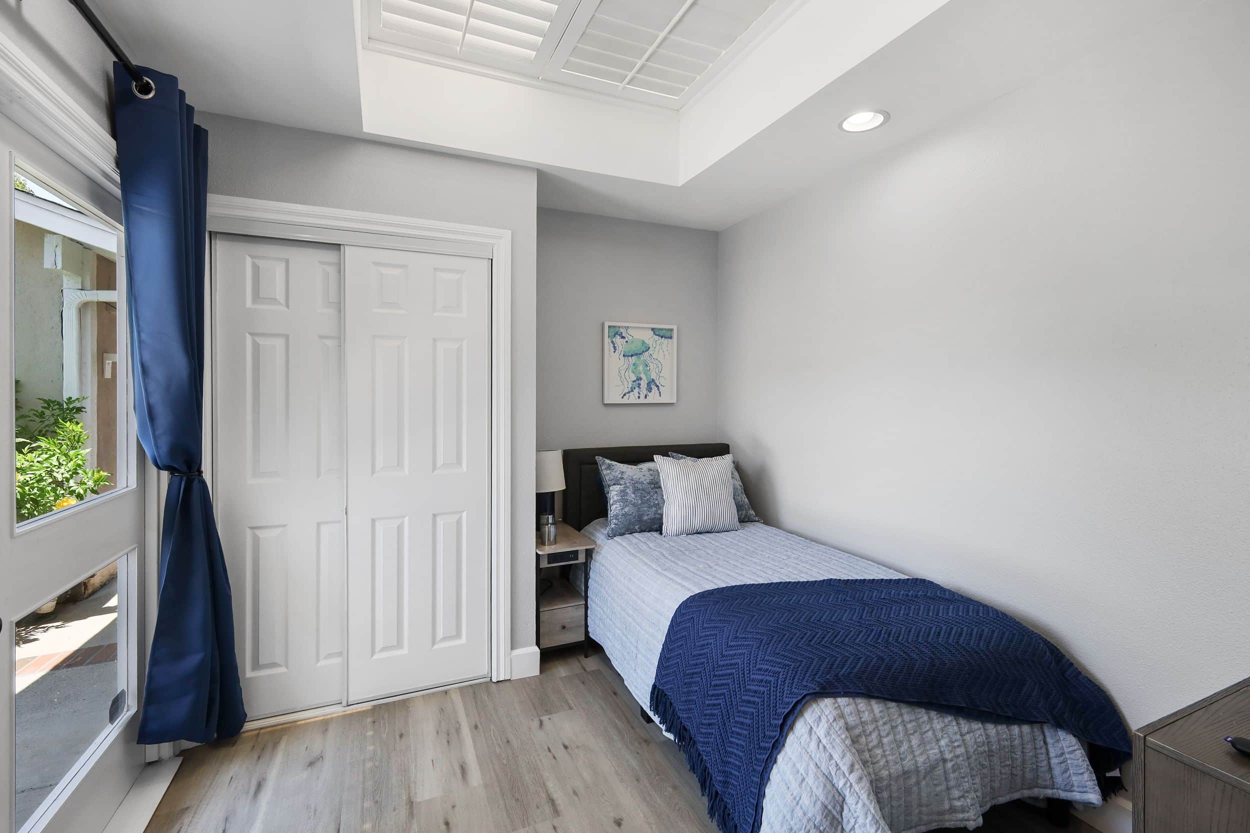 Modern bedroom with single bed, blue bedding, and artwork on the wall.