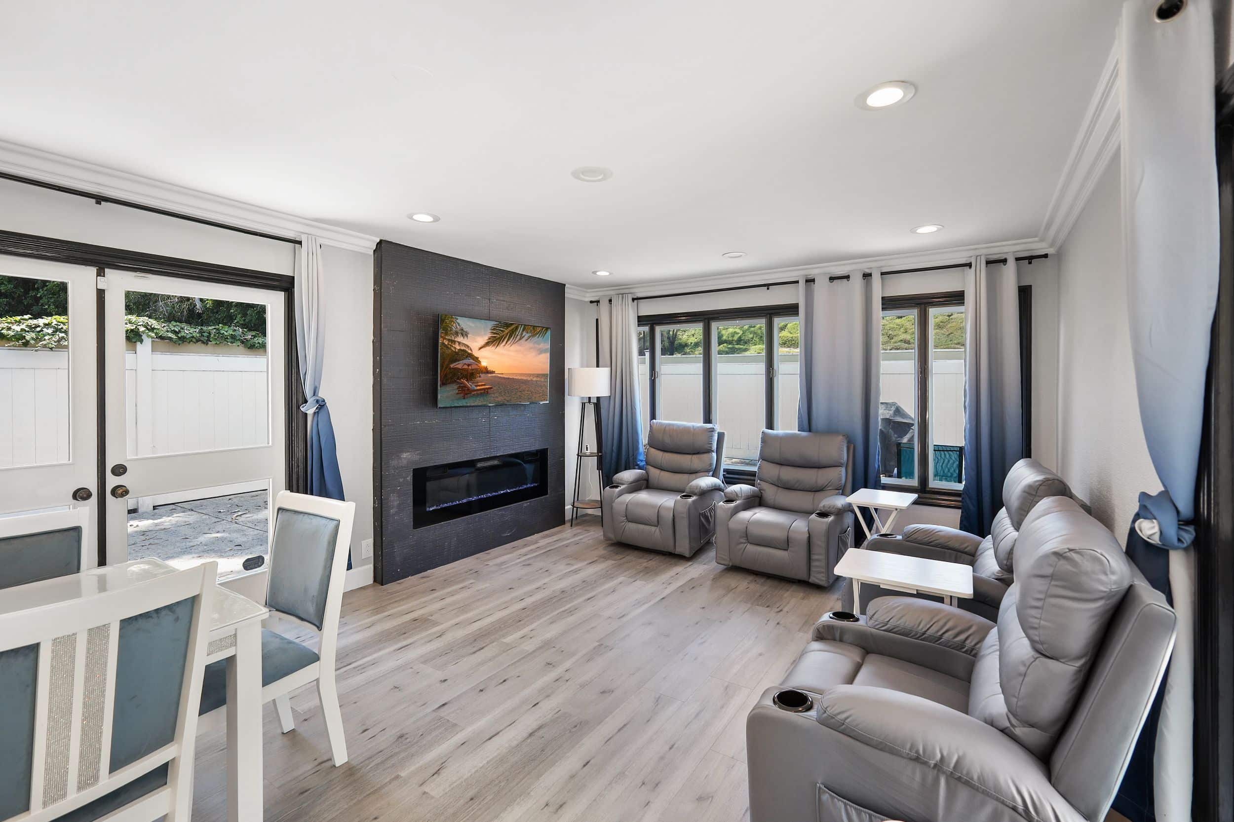Modern living room with gray recliners, flat-screen TV, and elegant decor.
