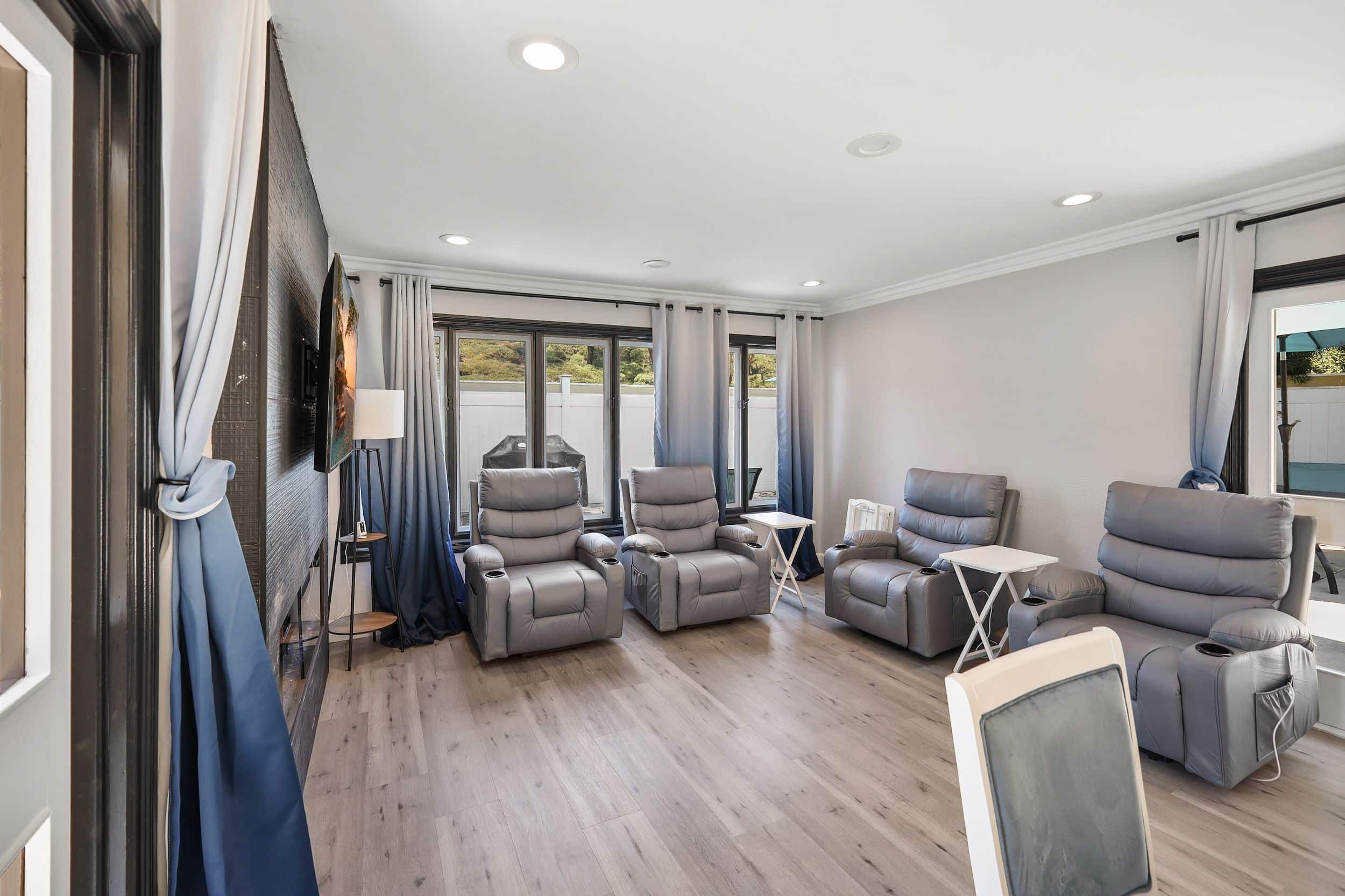 Modern lounge with gray recliners, white tables, and blue gradient curtains.