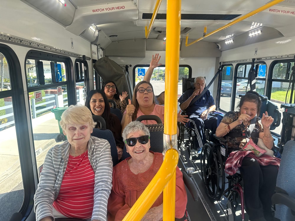 People smiling and sitting inside a bus, enjoying a group outing.