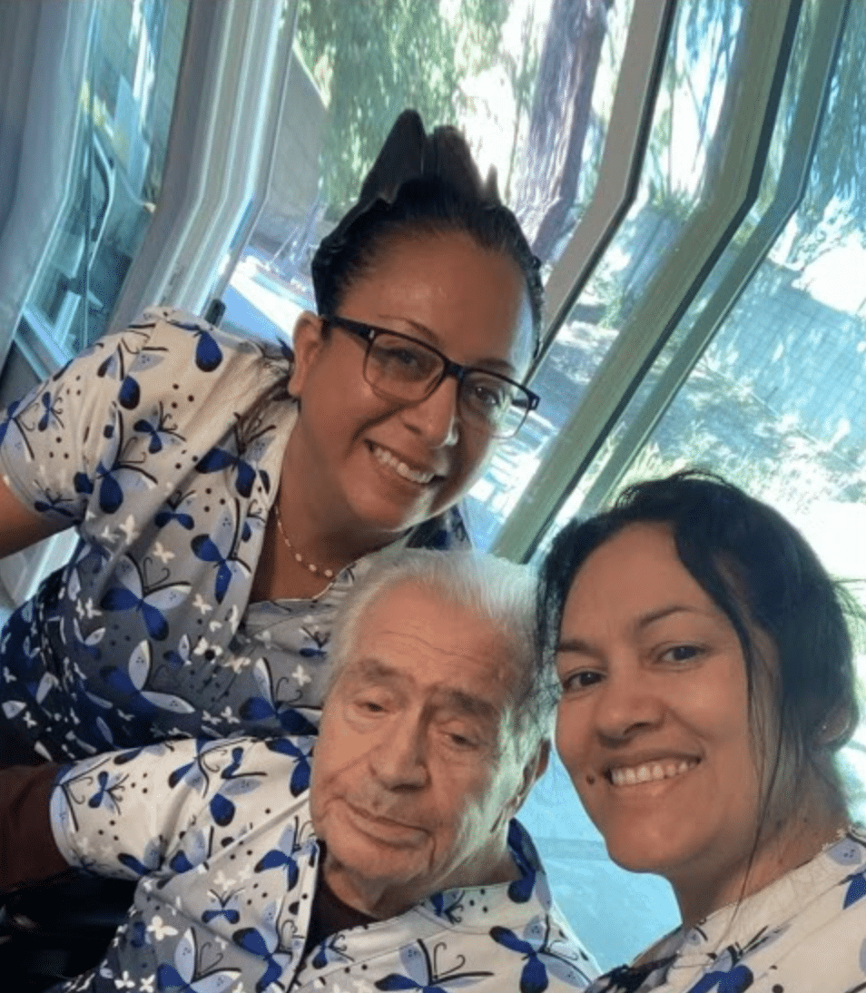 Three people in matching butterfly shirts smiling indoors.
