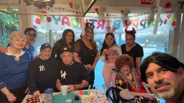 A group of people celebrating a birthday with a banner and decorations.